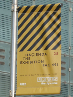 A bright yellow Hacienda exhibition banner outside Urbis