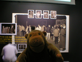 Mr Monkey looking at large pictures of the inside of the Haçienda