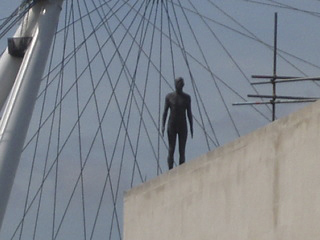 An Event Horizon Gormley on top of the Royal Festival Hall with the spokes of the London Eye in the background