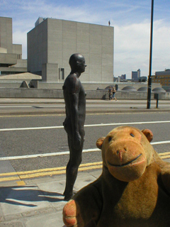 Mr Monkey looking at a Gormley figure from the side