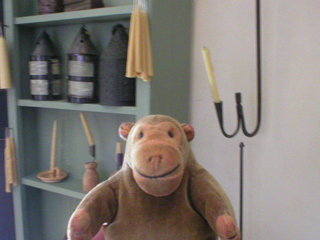 Mr Monkey looking at shelves of candles and lanterns