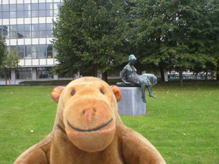 Mr Monkey looking at a statue of a seated woman