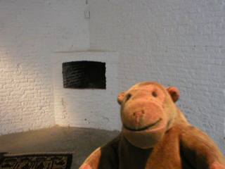 Mr Monkey looking at fireplace in a corner