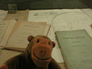 Mr Monkey looking at a case of pamphlets and maps