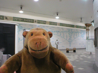 Mr Monkey looking at the decorative wall of Hammersmith Underground station