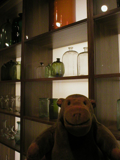 Mr Monkey looking at a collection of glass bottles