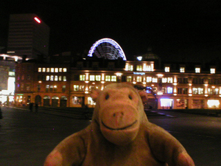 Mr Monkey looking the Wheel of Manchester over the roof of the Triangle
