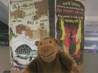 Mr Monkey looking at posters advertising East Timor as a destination