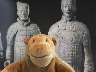 Mr Monkey in front of a picture of two terracotta soldiers