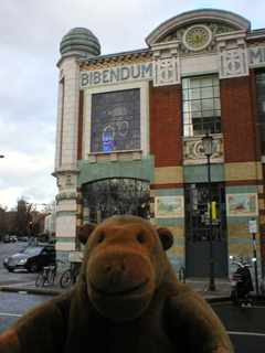 Mr Monkey looking at stained glass showing Bibendum on a bicycle