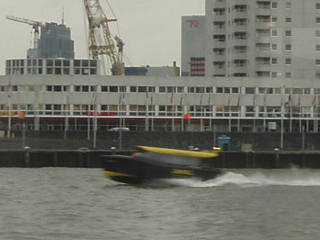 A water taxi speeding past the Boompjes