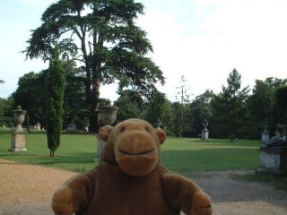 Mr Monkey in front of a lawn bordered with urns
