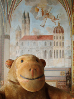 Mr Monkey in front of a photo of a wall painting at Vyšehrad