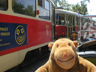 Mr Monkey in a car beside a Prague tram