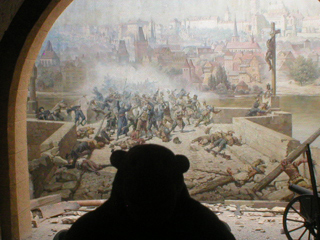 Mr Monkey studying a mural showing fighting in the Thirty Years War