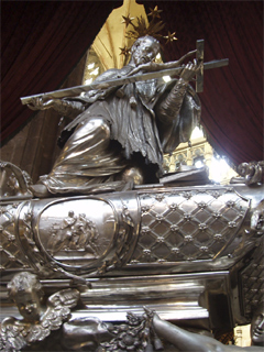 A silver St John Nepomuk on top of his monument