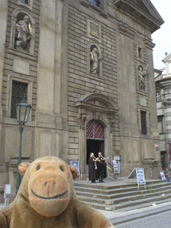 Mr Monkey watching trumpeting monks on the steps of the Church of St Francis