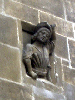 A carved man leaning out of the Powder Tower