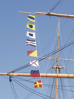 Signal flags spelling DISCOVER hanging from the yards of HMS Warrior