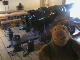 Mr Monkey looking at an Armstrong 110 pounder rifled breech-loader on the gun deck