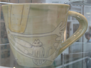 A cat and two people on the side of a mug by Vivienne Ross