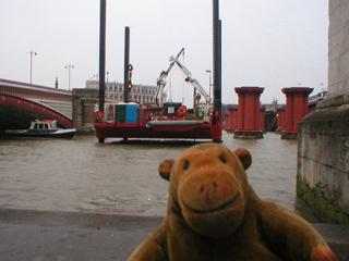Mr Monkey watching a crane in the Thames beside Southwark bridge
