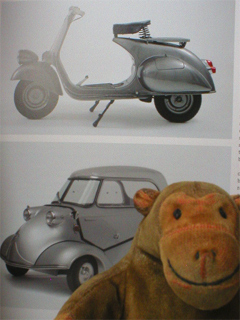 Mr Monkey in front of photos of Vespa 125cc motorscooter and a Messerschmitt KR 200