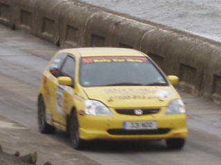 A rally car speeding beside the sea