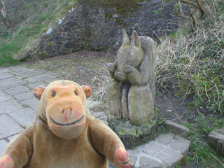 Mr Monkey looking at a giant wooden squirrel on the old platform