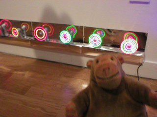 Mr Monkey looking at a row of spinning illuminated fans