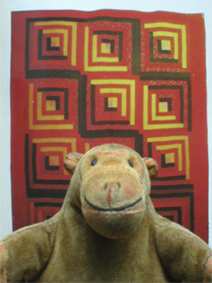 Mr Monkey looking at a picture of a straight furrow log cabin pattern quilt