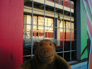 Mr Monkey looking through a viewing window in the Bristol Museum hoarding