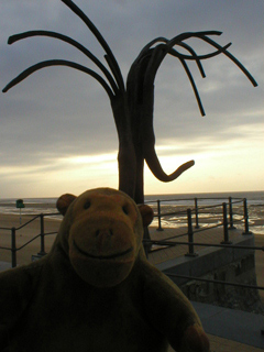 Mr Monkey looking at the Dancing Waves sculpture on the promenade