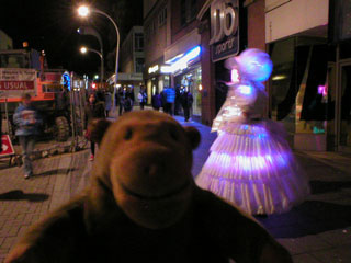 Mr Monkey looking at a pair of illuminated people from the parade