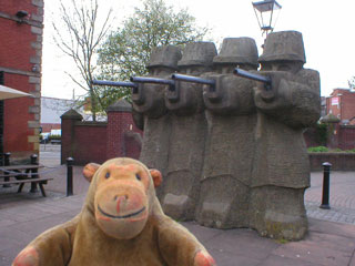 Mr Monkey looking at the statue of the soldiers shooting the workers