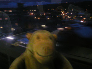 Mr Monkey looking at the lights of a town from the train