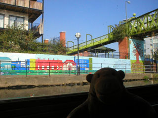 Mr Monkey looking at the mural of Mancunian buildings