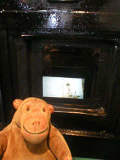 Mr Monkey looking through the projectionist's peephole to see the cinema screen