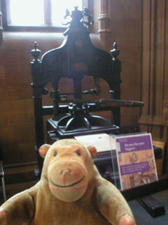 Mr Monkey looking at a printing press in the entrance hall