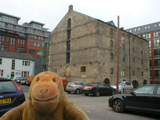 Mr Monkey looking at the Rochdale Canal Company warehouse  in the Dale Street carpark