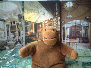 Mr Monkey in front of some postcards from the Soane museum