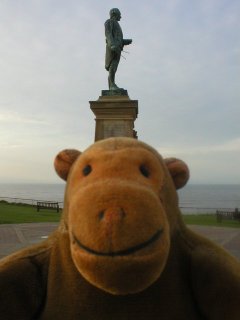 Mr Monkey with the statue of Captain Cook behind him