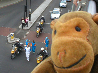 Mr Monkey watching a runner with the Olympic Flame