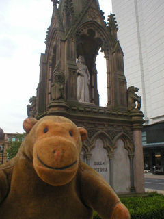 Mr Monkey beside a monument to Queen Victoria
