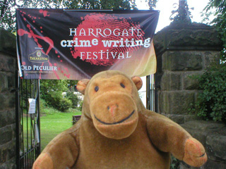 Mr Monkey with a large banner advertising the Harrogate Crime Writing Festival