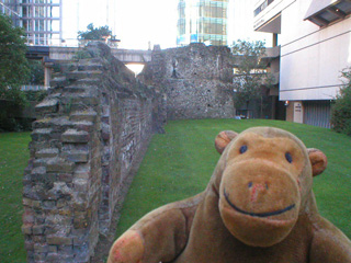 Mr Monkey beside a length of crumbling wall