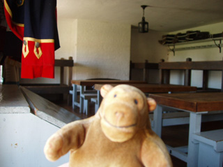 Mr Monkey beside a soldier's tunic in a barracks of bunk beds