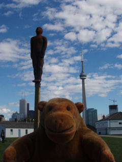 Mr Monkey in front of a child-bear on a pole with the CN Tower in the distance