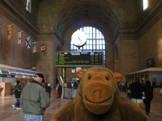 Mr Monkey checking train times in the booking hall of Union Station