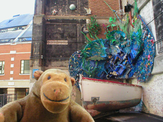 Mr Monkey in front of a boat and fishes sculpture